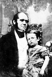 Darwin nos seus trinta anos, com seu filho vestido com um vestido que senta-se em seu joelho.