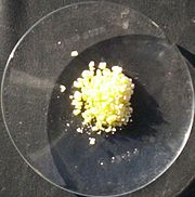 Relógio de vidro sobre uma superfície preta com uma pequena porção de cristais amarelos