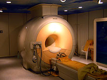 Quarto de alta máquina médica amarelo-acinzentado com um furo homem-size no meio e uma maca diretamente na frente dele