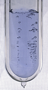 Uma garrafa de vidro meio-cheio com um líquido borbulhante azulada
