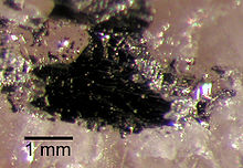 A massa escura, cerca de 2 milímetros de diâmetro, sobre um substrato de cristal cor-de-rosa