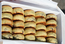 24 pãezinhos em marrom dourado são colocados em uma caixa retangular branco. Os pães são organizadas como um ábaco.