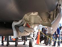 Close-up view of open aircraft weapons bay. The aircraft mock-up itself is on display, watched on by onlookers.