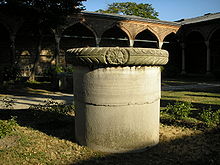 Uma coluna stout cilíndrico em um pátio em frente de arcos palacianos de estilo islâmico