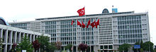 Um prédio de escritórios de altura média envidraçadas, com uma variedade de bandeiras turcas na frente.