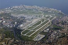 An aerial view of an airport with three runways and several taxiways arranged around a terminal