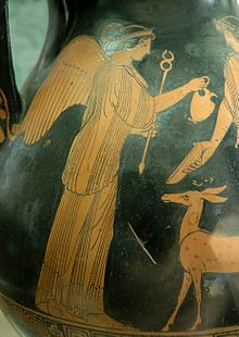 Foto de parte de um vaso preto com imagem marrom sobre ele: Uma mulher com asas nas costas mantenha uma flecha com a mão direita e dá um frasco com um homem. Um pequeno cervo está estando na frente da mulher.