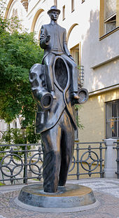 The statue is a man with no head or arms, with another man sitting on his shoulders.
