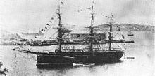Navio de guerra de três mastros fundeado em uma baía.