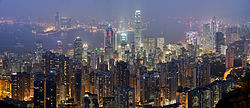 Um panorama com vista para os arranha-céus de Hong Kong na noite, com Victoria Harbour em segundo plano