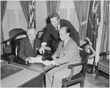 Three men at a desk reviewing a document