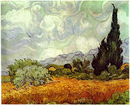 An open field of yellow wheat, under swirling and bright white clouds in an afternoon sky. A large cypress tree to the extreme right painted in shades of dark greens with swirling and impastoed brushstrokes. There are several smaller trees to the left and around the cypress tree are more small trees and several haystacks. There are blue-gray hills on the horizon in the background.
